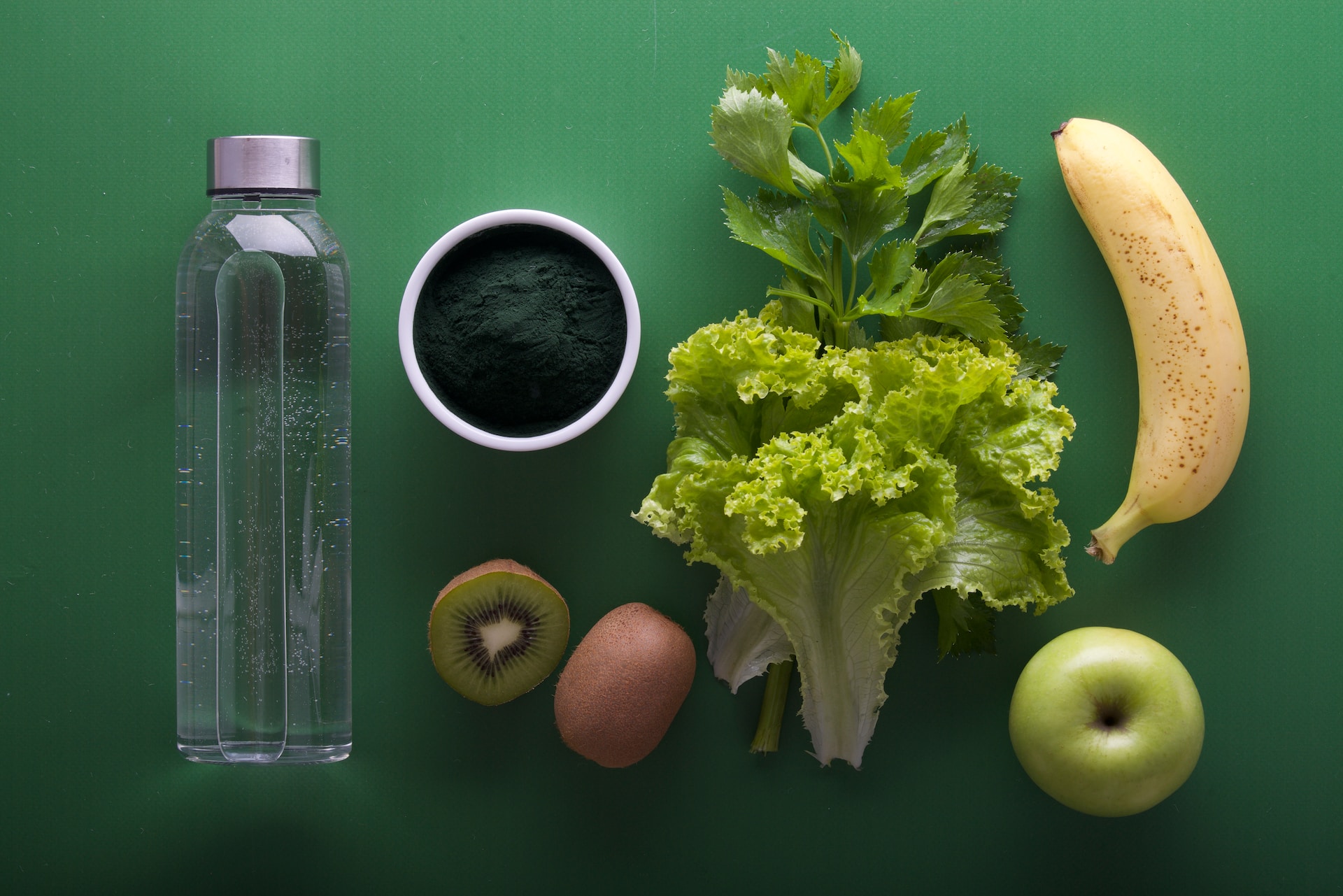 the image shows fruits, greens and a bottle of water