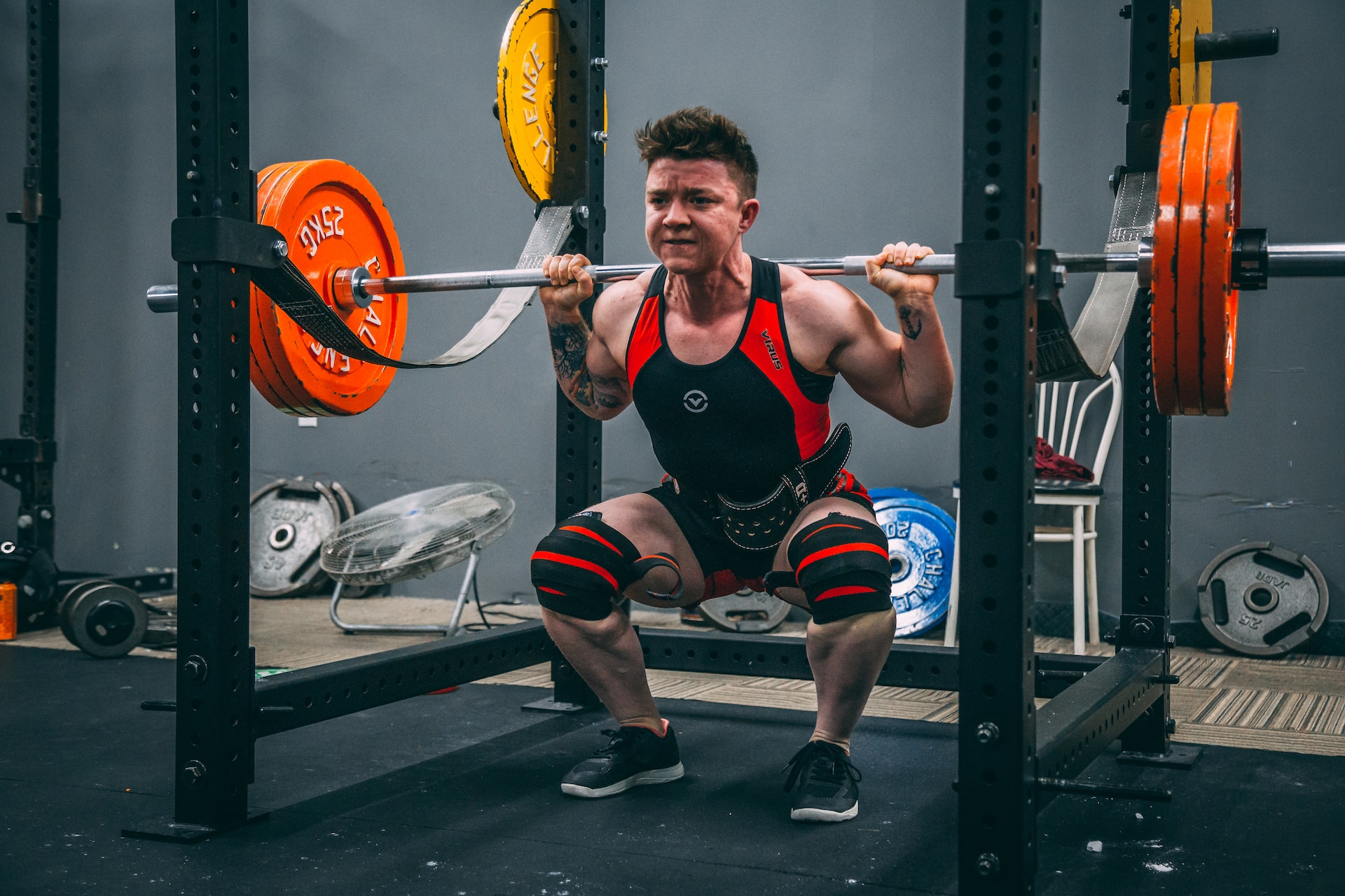 the image shows an athlete doing barbell squats at the gym