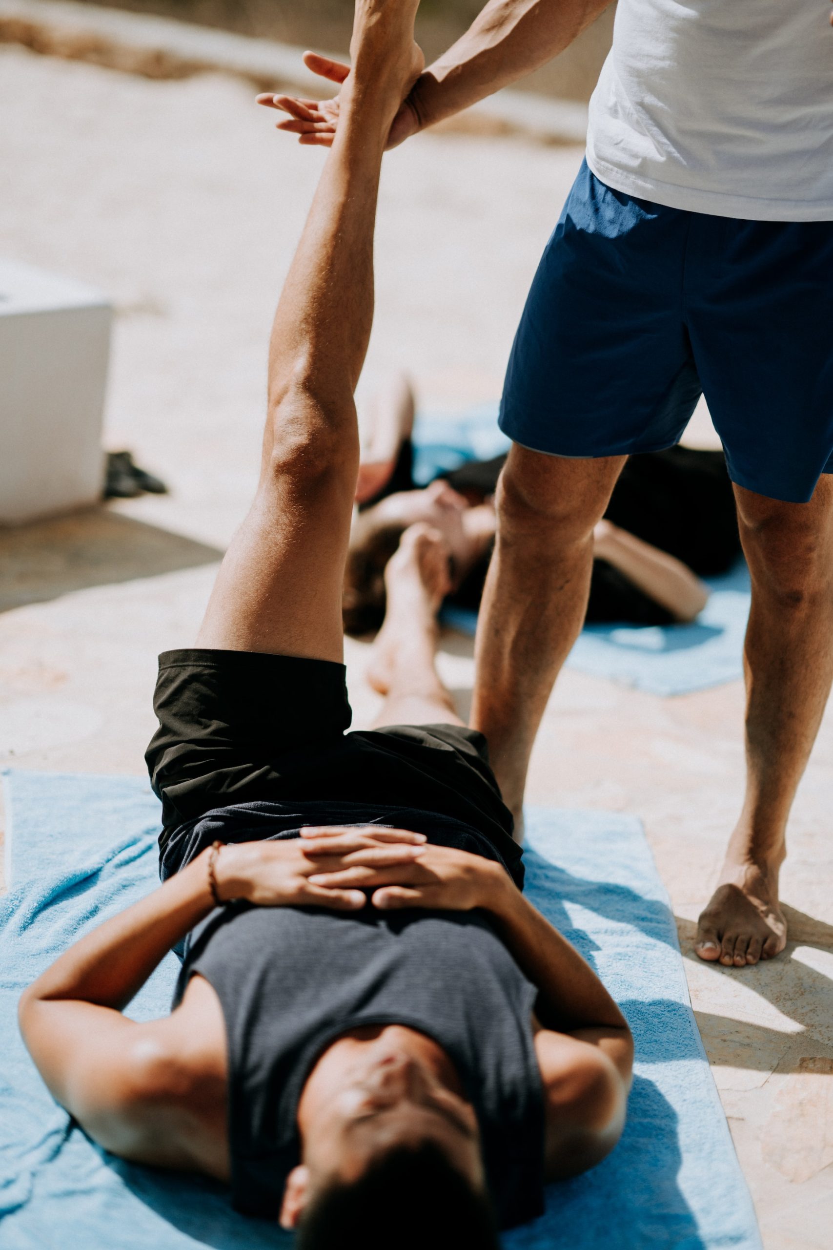 the image shows a trainer helping a man with a stretching