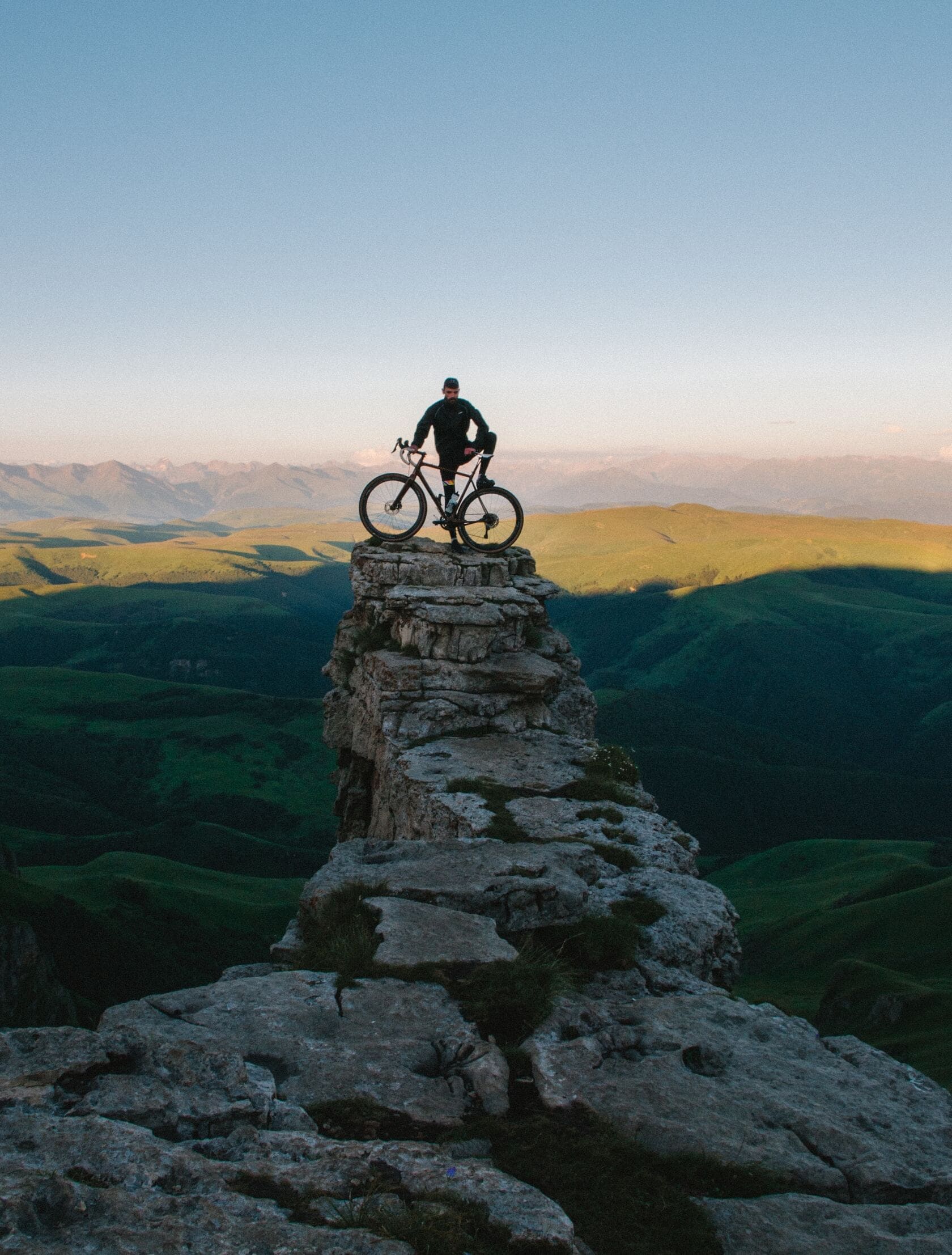 the image shows a man with a bike standing on the cliff