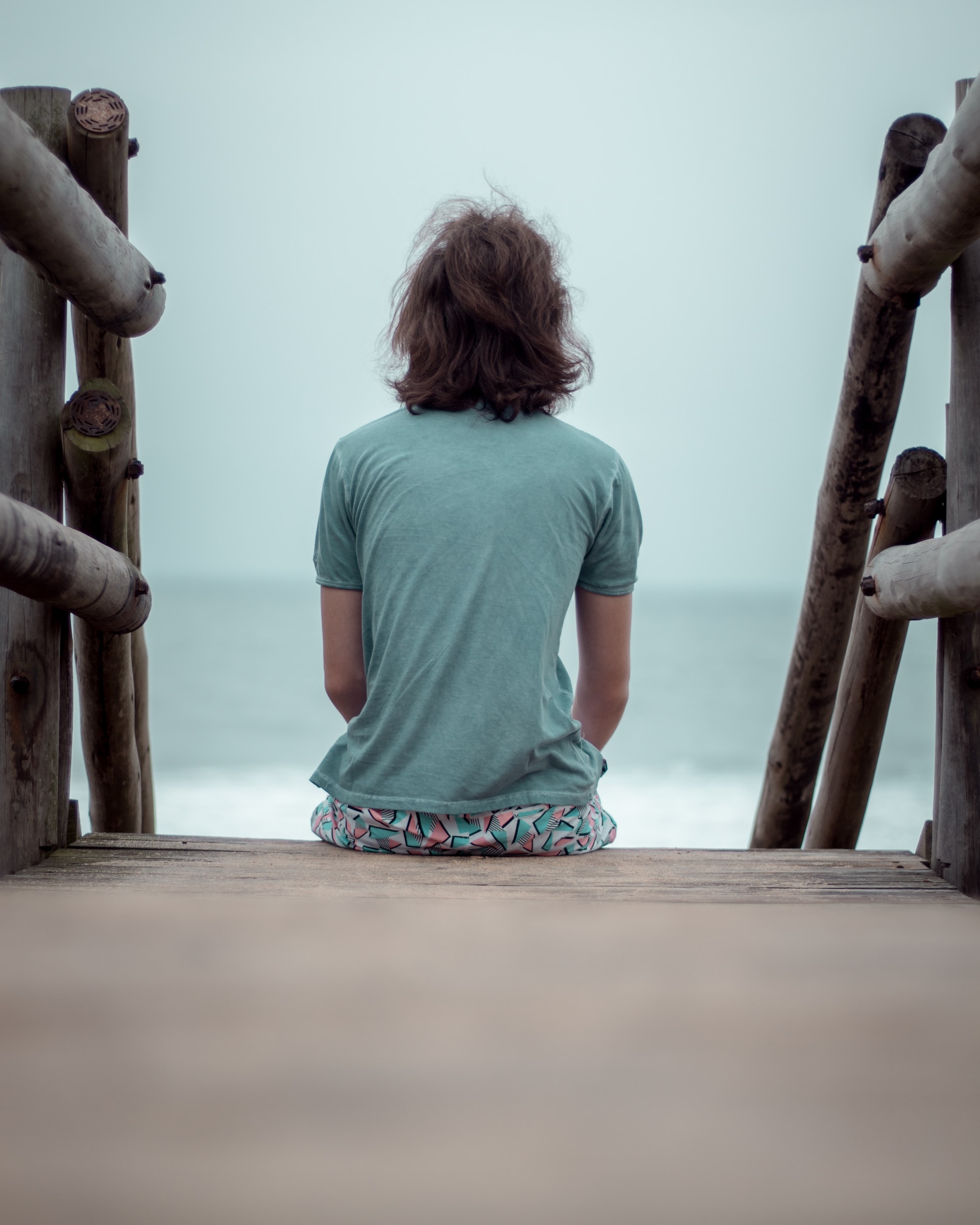 the image shows a man sitting on the pier