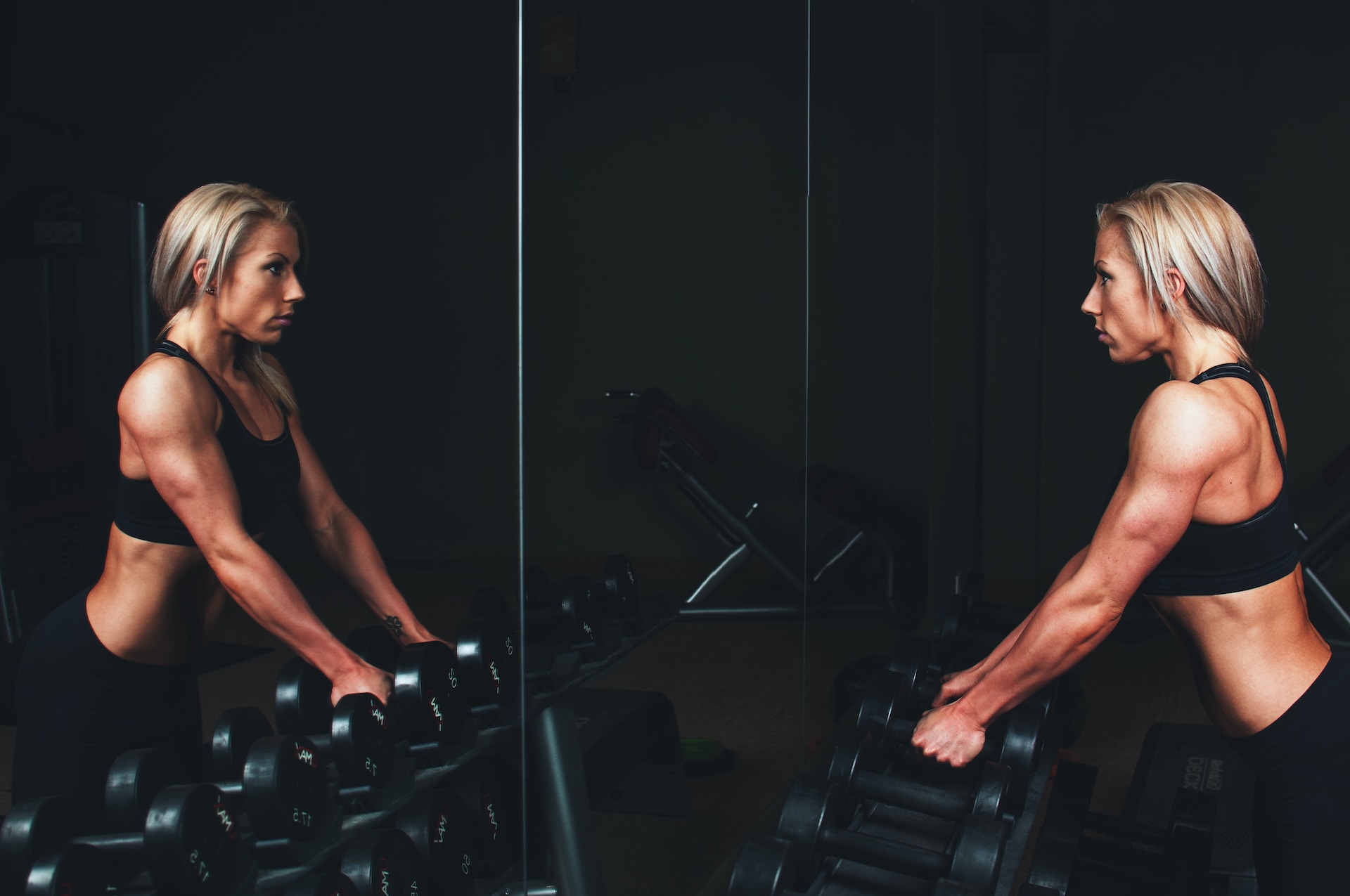 the image shows a woman standing next to the mirror at the gym