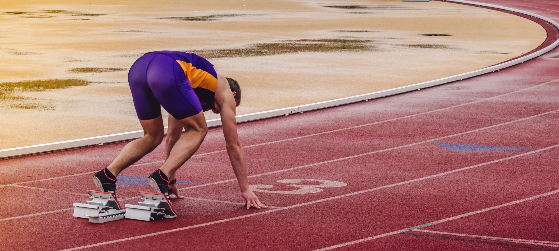 the image shows a male runner standing at the low start