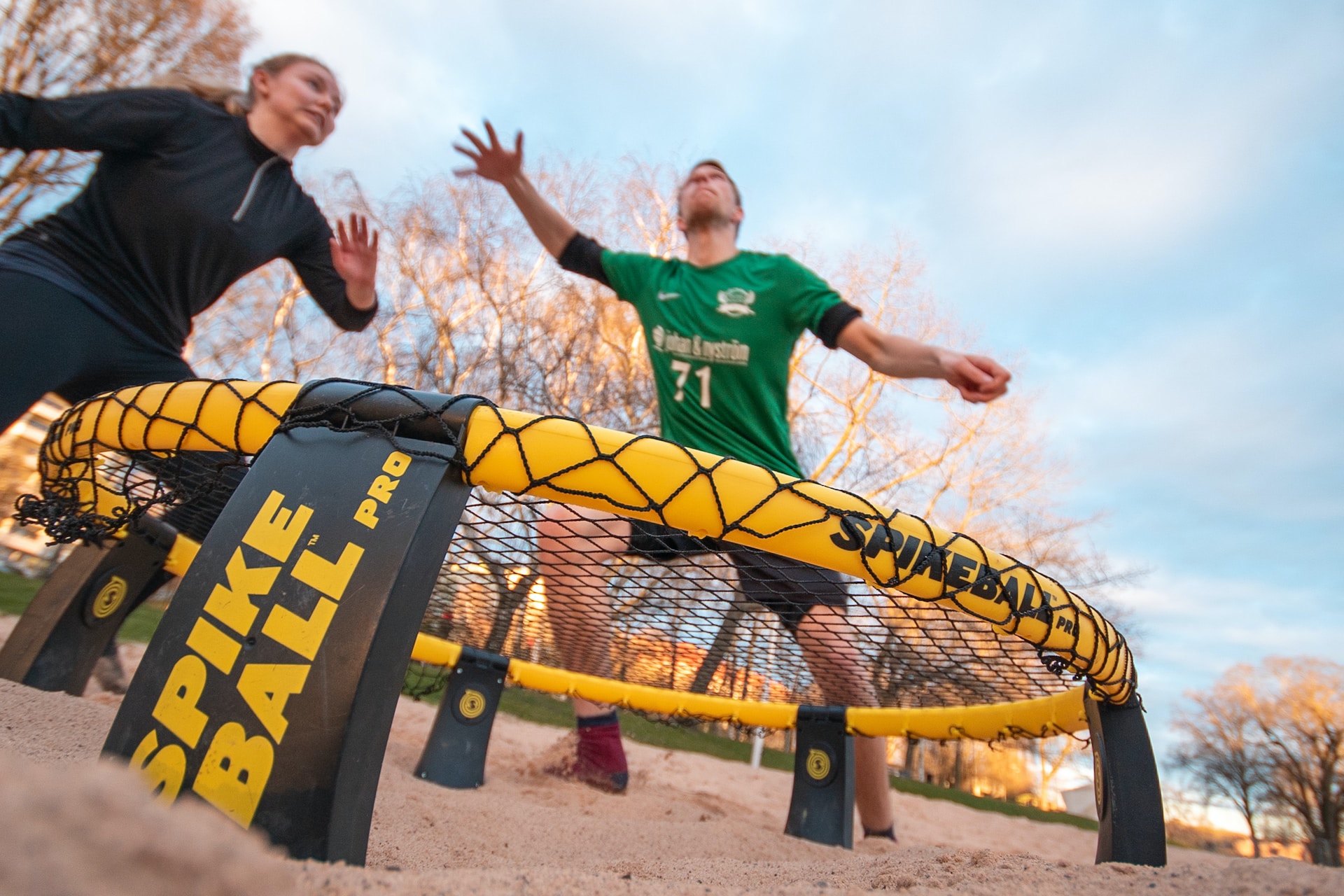 the image shows a man and a woman playing a spikeball 