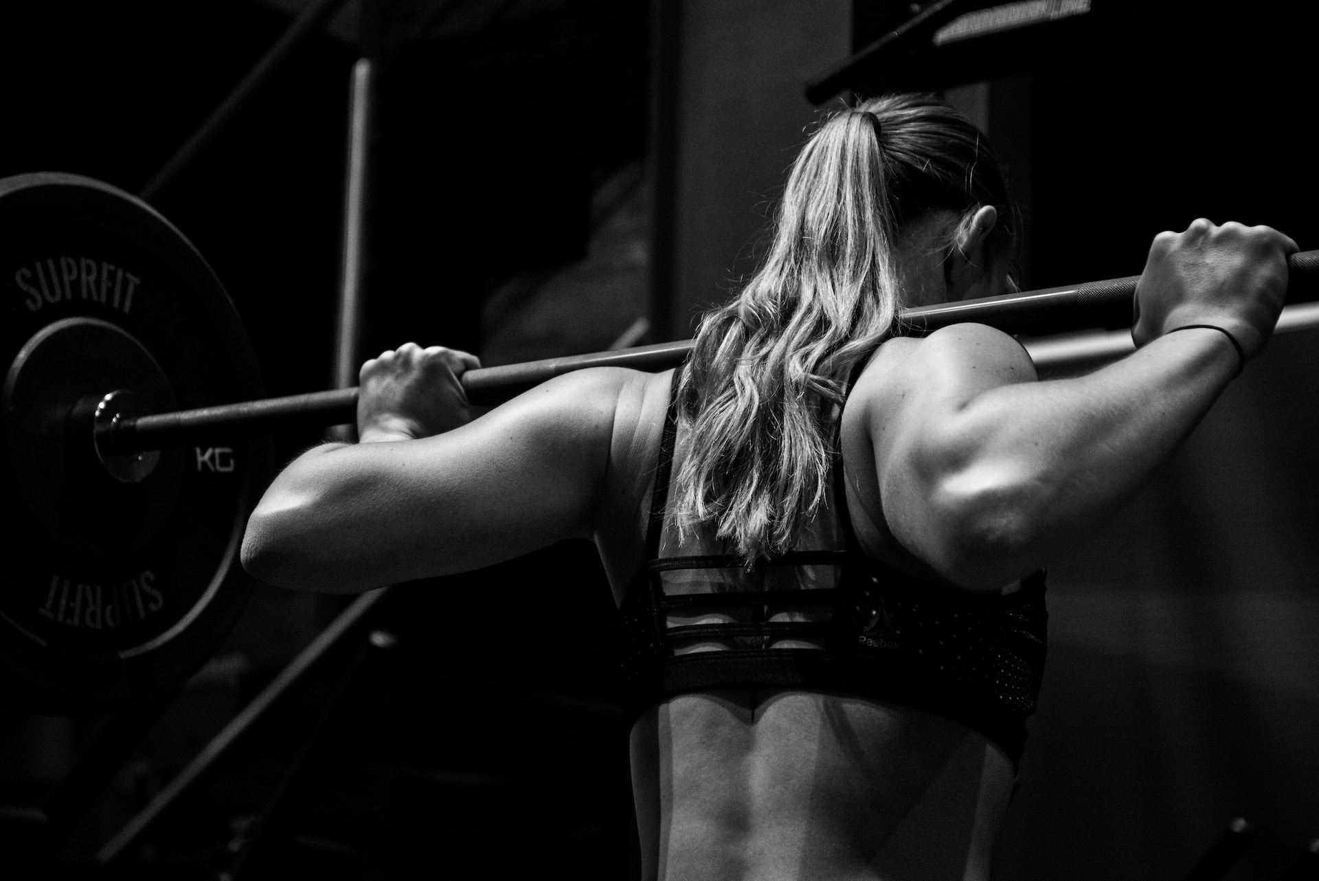 the image shows a female athlete lifting a barbell